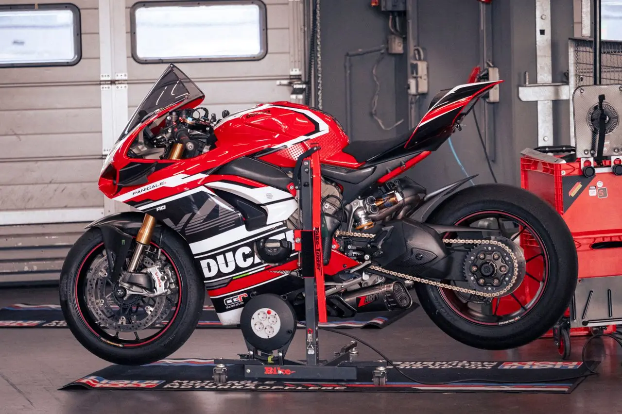 Teknik Özellikler 1 A vibrant red Ducati Panigale motorcycle in a Nürburgring garage setting.
