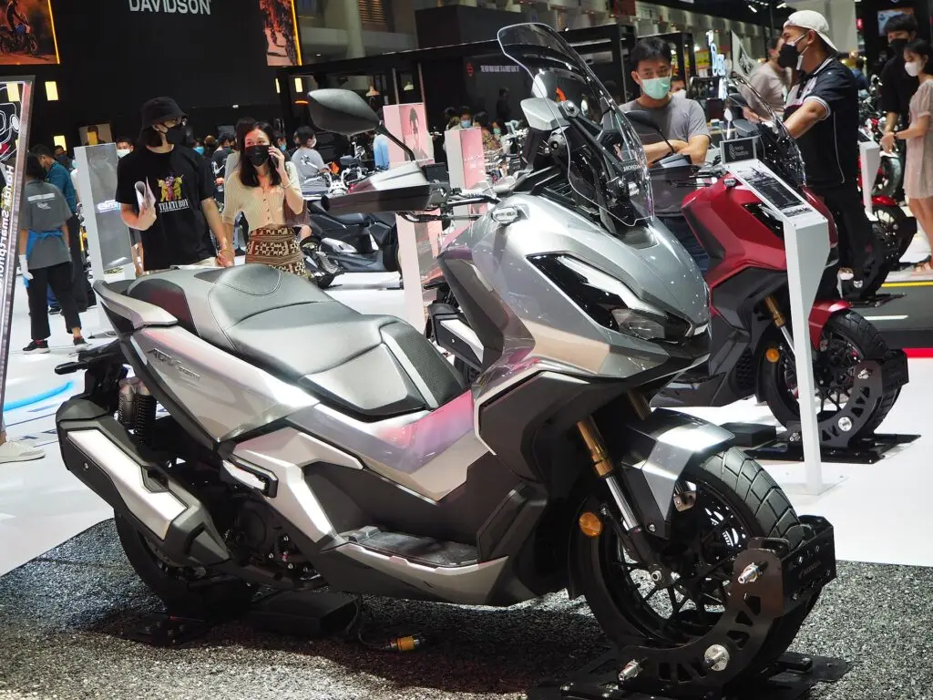 Gri Honda ADV 350 maksi scooter, fuar standında ön çeyrek açıdan