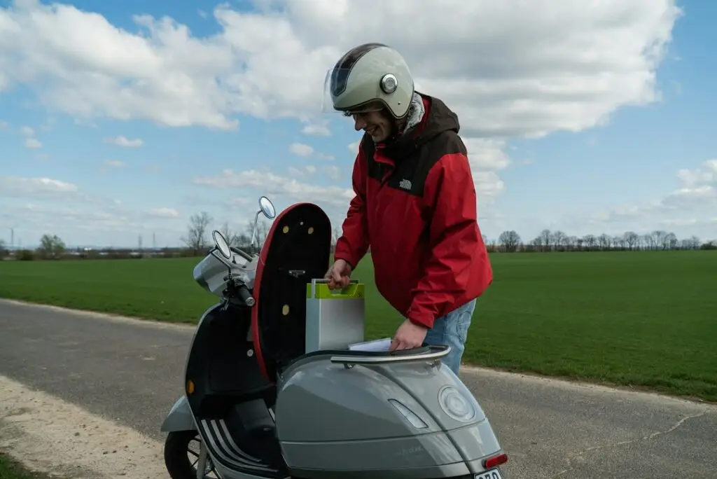 Kırmızı montlu s&uuml;r&uuml;c&uuml; g&uuml;nd&uuml;z elektrikli scooter kullanıyor